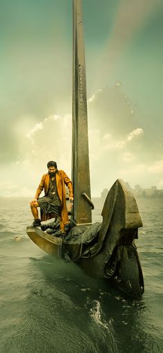 a man sitting on top of a boat in the ocean next to a tall pole