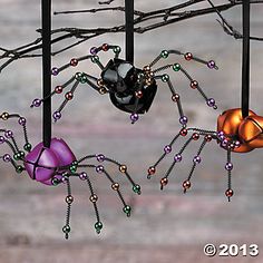 three halloween decorations hanging from a tree with spider legs and balls on it's back