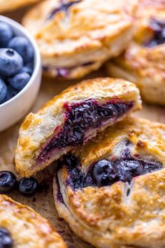 blueberry pies cut in half and placed next to a bowl of blueberries