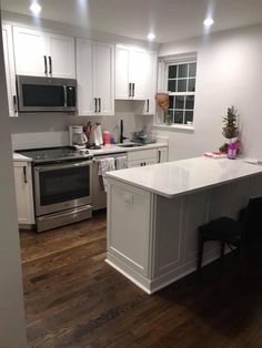 a kitchen with white cabinets and an island in the middle, along with stainless steel appliances