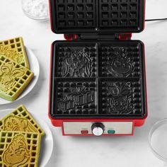 two waffle irons sitting next to each other on a white table with plates and glasses