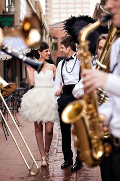 a man and woman standing next to each other with musical instruments in their hands on the sidewalk