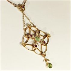 The colors of the holiday's sparkle in this Edwardian necklace! Hand crafted in 9 karat gold, this necklace is set with two sparkling green peridot gems and five bright red garnets. The drop of this necklace is 63 mm long and 33 mm across and the chain measures 14.5 inches long and closes with a barrel clasp. The necklace is marked '9c' for 9k gold. The gold has a rosy hue. This necklace weighs 7 grams. Made in England around 1900-1910. This lovely necklace has a light and airy feel and yet is s Yellow Gold Multi-stone Necklace For May Birthstone, Gold Multi-stone Necklace For May Birthstone, Fine Jewelry Green Multi-stone Necklace, Green Multi-stone Fine Jewelry Necklace, Green Multi-stone Fine Jewelry Necklaces, May Birthstone Multi-stone Pendant Necklace, Formal Peridot Pendant Necklace, Peridot And Garnet, Edwardian Necklace