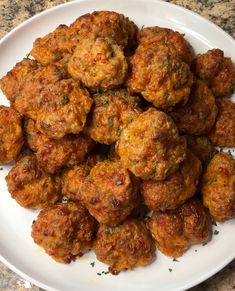 a white plate topped with meatballs on top of a marble countertop covered in parsley