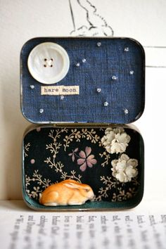 an orange cat sleeping in a blue case with flowers on the side and a white button