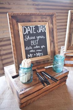 a couple of jars sitting on top of a wooden table next to a chalkboard