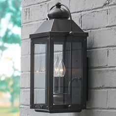 an outdoor wall light with two lights on the side of it, against a brick wall