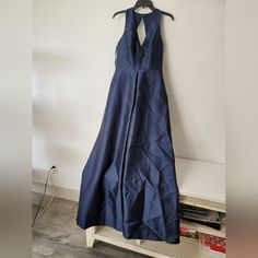 a blue dress hanging up against a wall next to a book shelf with magazines on it