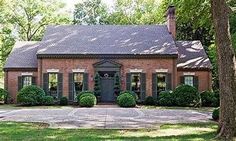 a brick house surrounded by trees and grass