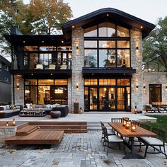 an outdoor dining area in front of a large house with stone walls and flooring