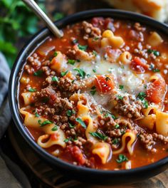 a bowl of pasta soup with meat and cheese on the side, ready to be eaten