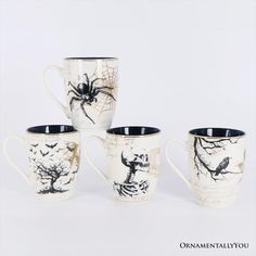 four coffee mugs decorated with black and white designs, one has a spider on it