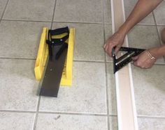 a person is using a pair of scissors to cut up a piece of tile on the floor