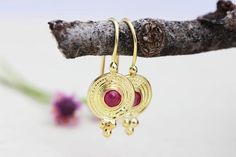 Exquisite, antique-style ruby and 14k, 18k or 22k solid gold hook drop earrings, Indian boho chic jewelry gift. These amazing drop earrings have a decorated rustic disc and a red ruby set in the middle of it. At the bottom of the disc on each earring, there are three gold dots that add character to these boho earrings. These earrings are elaborate and delicate but still very noticeable. They have a unique eye-catching boho look that will go with and upgrade any outfit.Ruby is the birthstone of J Gold Ruby Round Earrings, Gold Ruby Earrings, Pierced, Gold Earrings With Ruby Gemstone, Gold Ruby Gemstone Earrings, Gold Ruby Earrings With Gemstone, Gold Ruby Earrings With Latkans, Yellow Gold Ruby Dangle Earrings, Gold Ruby Earrings, Ruby Drop Earrings