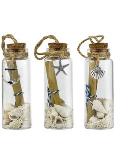 three glass jars with sand, shells and starfish in them on a white background