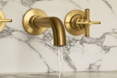 two faucets with water running from them on a marble counter top