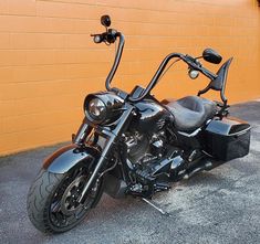 a black motorcycle parked in front of a yellow brick building with no one on it