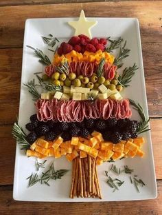 a christmas tree made out of fruits and vegetables on a white plate with rosemary sprigs