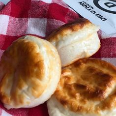 three biscuits sitting on top of a red and white checkered table cloth next to a bag