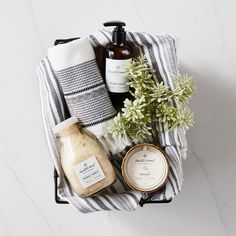 an assortment of personal care products sitting on a towel next to a potted plant