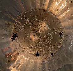 an upside down view of the bottom of a glass vase with water droplets and stars on it