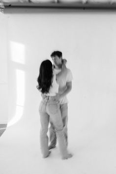 a man and woman kissing in front of a white background