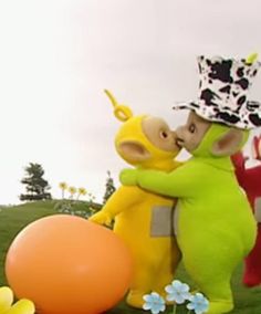 two cartoon characters hugging each other in front of an orange and yellow balloon with flowers