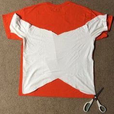 an orange and white t - shirt with scissors on the floor next to it that has been cut in half