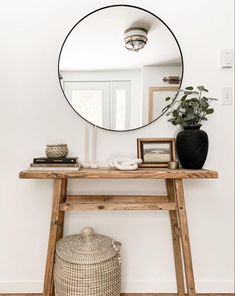 a mirror sitting on top of a wooden table next to a vase and potted plant