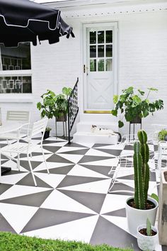 an outdoor patio with potted plants and white chairs on it's tiled floor