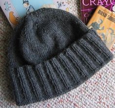 a gray hat sitting on top of a bed next to books