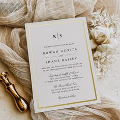 the wedding stationery is laid out on top of an antique bottle and some flowers