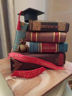 there is a stack of books with a graduation cap on top of it and a red ribbon in front of them