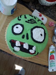 a green cake with white frosting on top of a wooden table next to other items