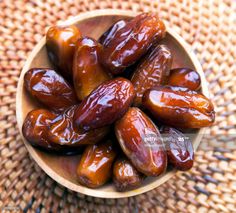 dates in a wooden bowl on a woven tablecloth