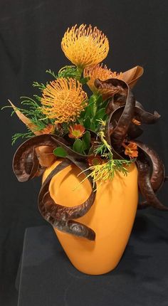 a yellow vase filled with flowers on top of a table