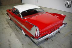 an old red and white car parked in a garage