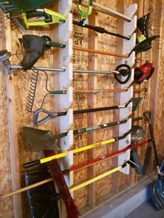 there are many different tools hanging on the wall in this room, including shovels and rakes