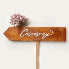 a wooden sign with the word ceremony written on it next to a bouquet of flowers