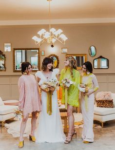 three bridesmaids in pastel colored dresses standing next to each other and laughing