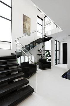 the stairs in this modern house are made of glass and wood, with black accents