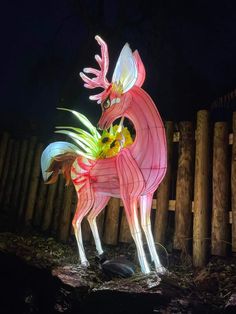 a lighted sculpture of a deer in front of a wooden fence