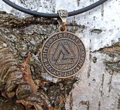 The Valknut is a symbol of God Odin in Norse mythology. Valknut means interlacing of 9 worlds. The pendant is made from Italian bronze solid by hand casting. The Valknut is depicted in the runes circle of Elder Futhark. This item will be perfect for Viking or Nordic jewelry likers. Item shipped in wooden jewelry box. !! Notice - Free necklace is made from rubber (caoutchouc) cord !! Size: Height: 45 mm. | 1 3/4 inch Width: 32 mm. | 1 1/4 inch Weight: 14 gm. | 0.5 oz Viking Style Handmade Gold Jewelry, Handmade Viking Gold Jewelry, Handmade Viking Style Gold Jewelry, Symbolic Bronze Jewelry With Coin Pendant, Symbolic Copper Pendant Jewelry, Symbolic Round Bronze Necklace, Gold Viking Style Jewelry, Gold Viking Style Necklace For Gift, Viking Style Bronze Jewelry Gift