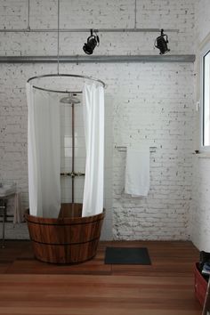 a bath tub sitting on top of a wooden floor next to a white brick wall