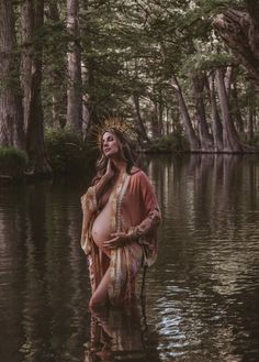 a woman standing in the water with her hands on her hips and wearing a crown