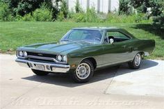 a green muscle car parked in a driveway