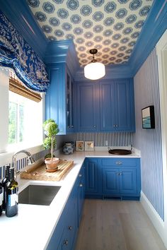 a kitchen with blue cabinets and white counter tops, along with a window above the sink