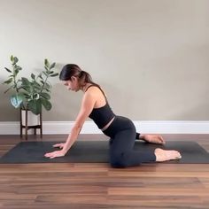 a woman is doing yoga on a mat in front of a potted plant and wall