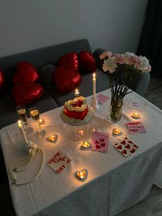 a valentine's day table with candles, cards and flowers on it in front of a couch