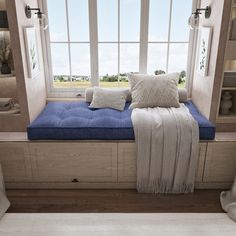 a window seat with pillows on it in front of a large window and bookshelf